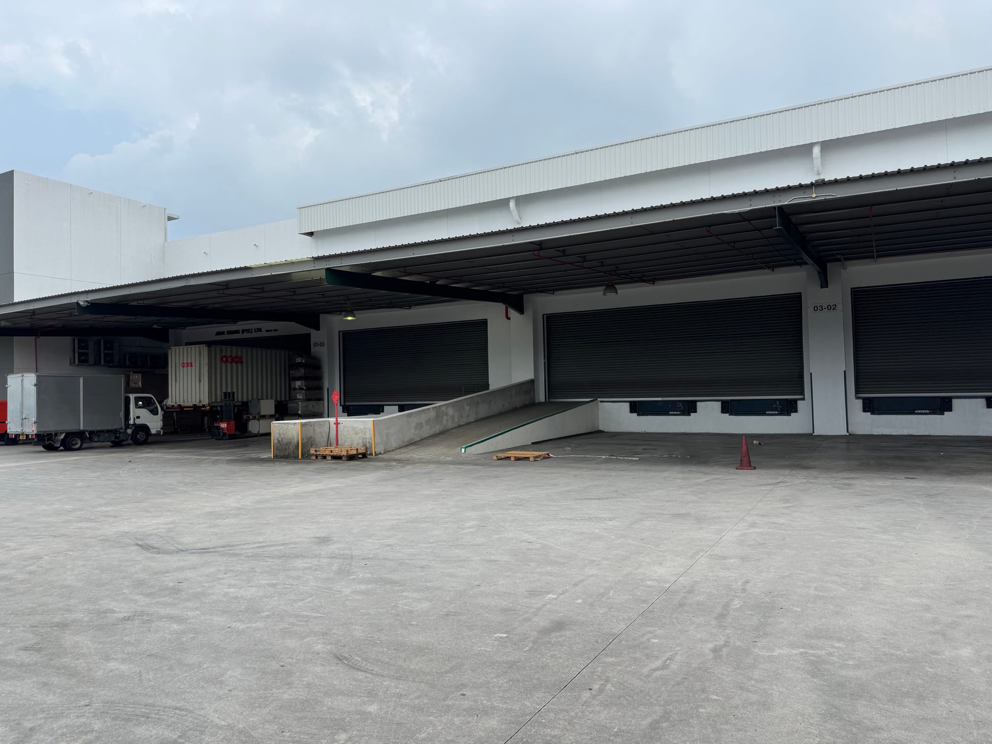 Loading platform with roller shutter doors, dock levellers and a container truck at bays 03-02 and 03-03